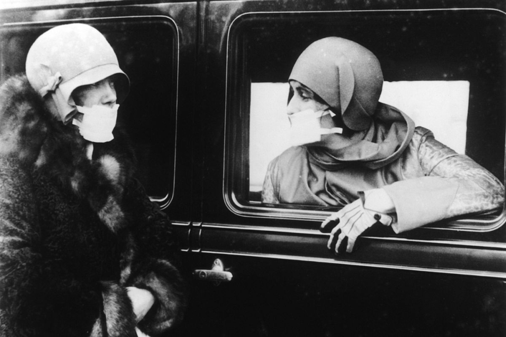 Două femei stau de vorbă cu măşti de tifon pe faţă în timpul epidemiei de gripă (1918)